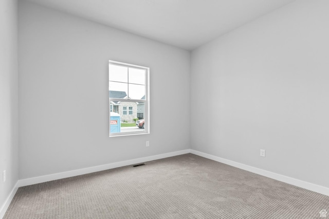 spare room featuring carpet flooring and baseboards