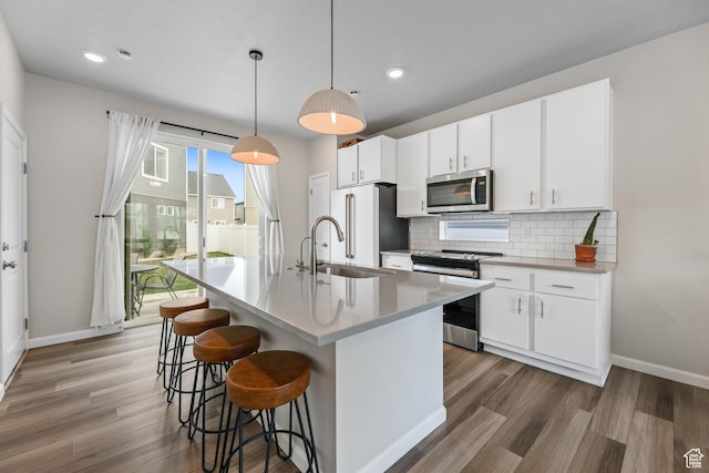 134 E Stroll Ave Unit 816, Saratoga Springs, UT 84045 - kitchen with a breakfast bar area, baseboards, appliances with stainless steel finishes, and light wood finished floors