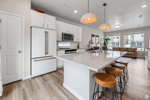 134 E Stroll Ave Unit 816, Saratoga Springs, UT 84045 - kitchen featuring a sink, open floor plan, a breakfast bar, stainless steel appliances, and white cabinetry