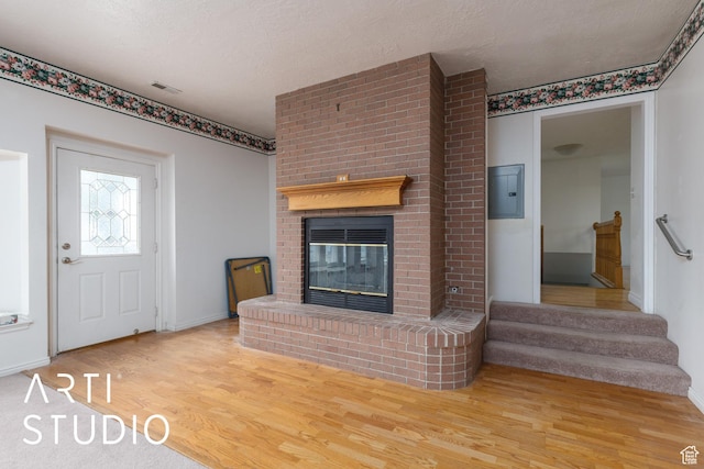 2732 S 4550 W, Taylor, UT 84401 - unfurnished living room with a brick fireplace, stairs, baseboards, wood finished floors, and electric panel