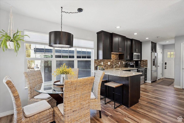 3511 N Willow Creek Ln E Unit 10, Eden, UT 84310 - kitchen featuring dark wood-style flooring, a sink, a breakfast bar area, stainless steel appliances, and backsplash