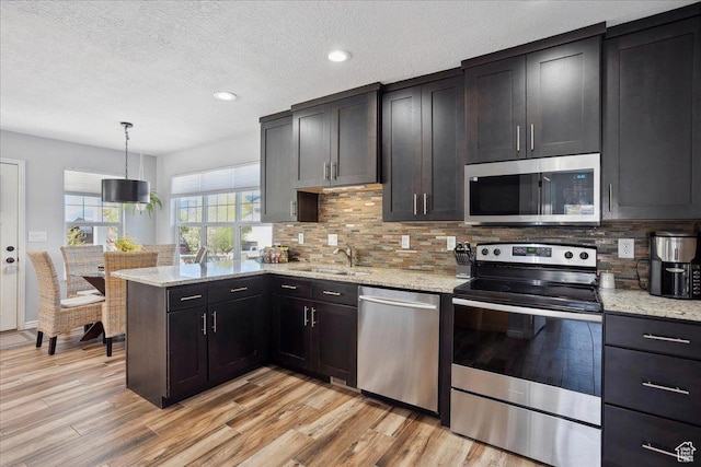 3511 N Willow Creek Ln E Unit 10, Eden, UT 84310 - kitchen featuring backsplash, light stone counters, a peninsula, light wood-style floors, and stainless steel appliances