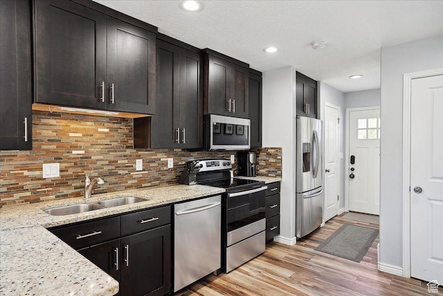 3511 N Willow Creek Ln E Unit 10, Eden, UT 84310 - kitchen featuring decorative backsplash, appliances with stainless steel finishes, a sink, light stone counters, and light wood-style floors