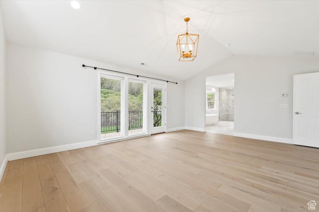 empty room featuring light wood finished floors, an inviting chandelier, baseboards, and lofted ceiling
