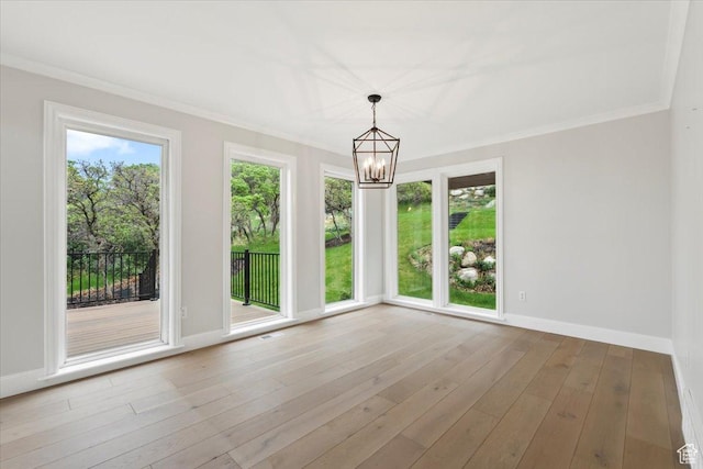 unfurnished dining area featuring baseboards, a chandelier, crown molding, and wood finished floors