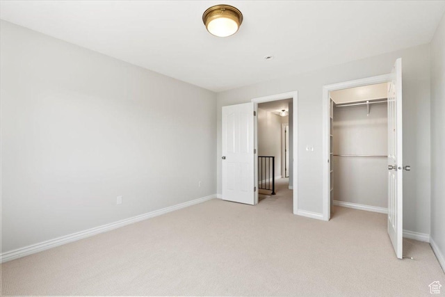unfurnished bedroom featuring a closet, light carpet, and baseboards