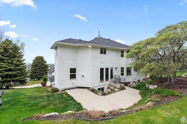 rear view of property featuring stucco siding and a lawn
