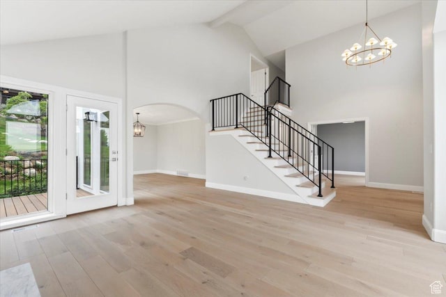 unfurnished living room with stairway, a chandelier, baseboards, and high vaulted ceiling
