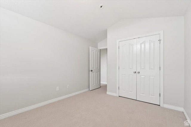unfurnished bedroom with vaulted ceiling, light colored carpet, baseboards, and a closet