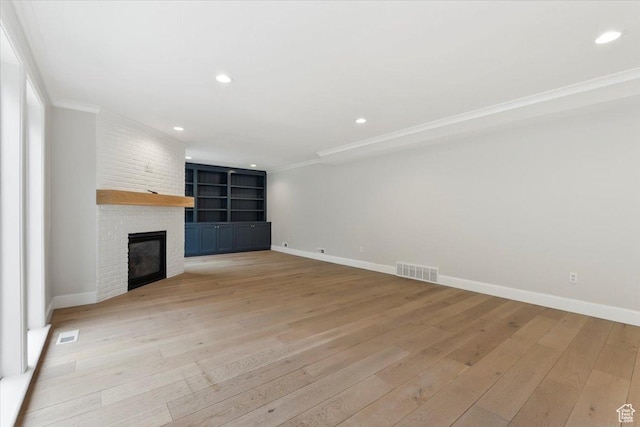 unfurnished living room featuring visible vents, crown molding, a brick fireplace, baseboards, and light wood-style floors