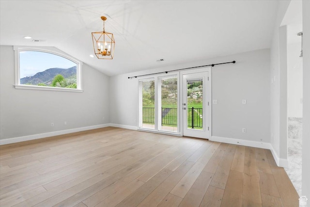 empty room featuring light wood-style floors, baseboards, a healthy amount of sunlight, and a notable chandelier