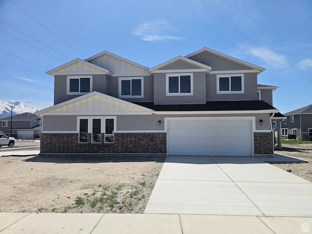 craftsman-style home with brick siding, a garage, board and batten siding, and driveway