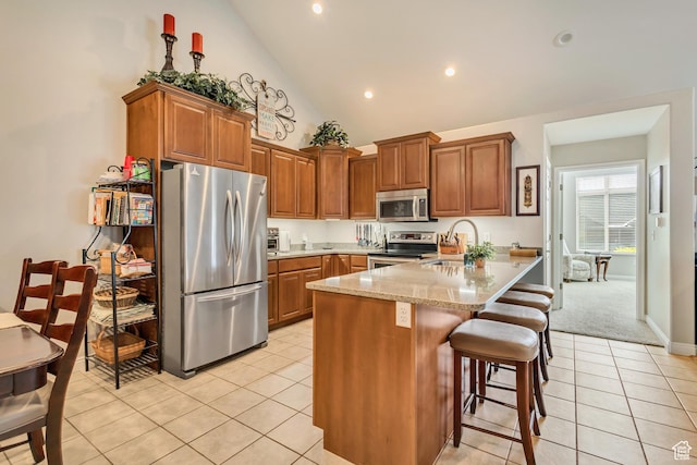 1889 S 910 W Unit B, Syracuse, UT 84075 - kitchen featuring brown cabinetry, a peninsula, a sink, light tile patterned floors, and stainless steel appliances