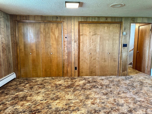 56 S 700 E, Hyrum, UT 84319 - unfurnished bedroom featuring wood walls, a textured ceiling, multiple closets, carpet flooring, and a baseboard radiator