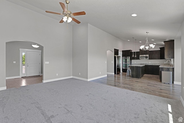 1350 S 849 W Unit 17D, Springville, UT 84663 - unfurnished living room with carpet flooring, arched walkways, a chandelier, a sink, and a towering ceiling