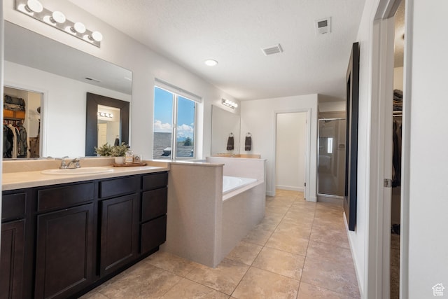 full bathroom featuring visible vents, a shower stall, a bath, and vanity