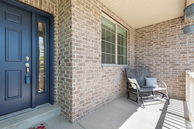 entrance to property with covered porch and brick siding