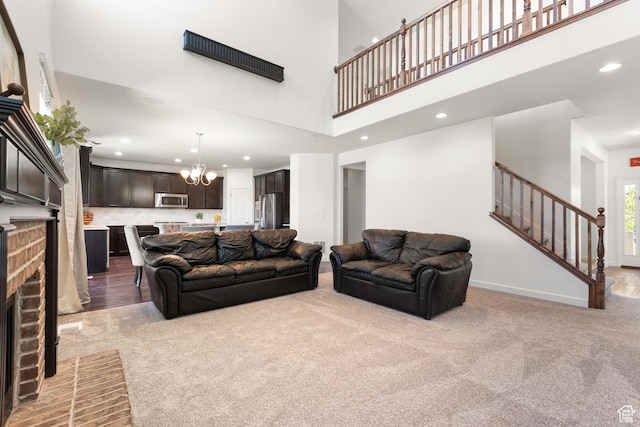 living area featuring an inviting chandelier, stairs, a brick fireplace, light carpet, and recessed lighting