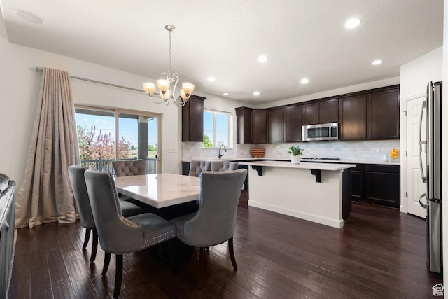 dining area with dark wood-type flooring, recessed lighting, and a notable chandelier