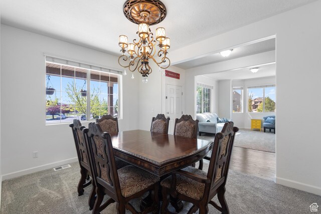 carpeted dining area with visible vents, baseboards, and an inviting chandelier