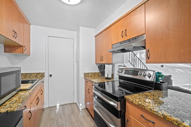 1167 W 4300 S Unit 27C, Taylorsville, UT 84123 - kitchen with under cabinet range hood, appliances with stainless steel finishes, stone counters, and light wood finished floors