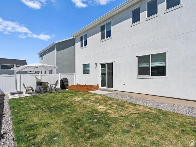 back of property with fence, stucco siding, a lawn, and a patio area