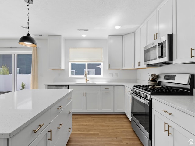 kitchen featuring visible vents, white cabinetry, a sink, light wood-style flooring, and appliances with stainless steel finishes