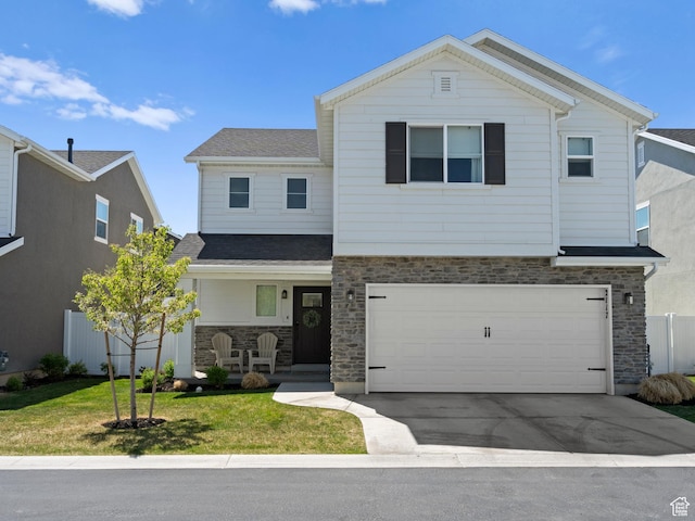 traditional home featuring a garage, stone siding, a front yard, a porch, and driveway