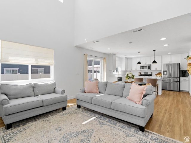 living room with recessed lighting, visible vents, and light wood-type flooring