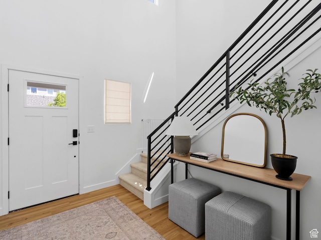 foyer entrance featuring baseboards, light wood finished floors, and stairs
