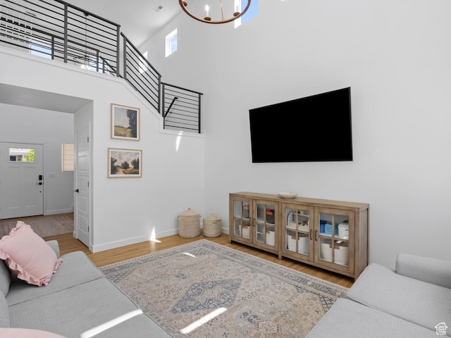 living area with an inviting chandelier, a high ceiling, baseboards, and wood finished floors