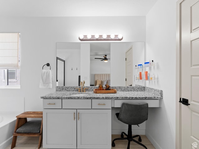 full bath with vanity, ceiling fan, baseboards, and a garden tub