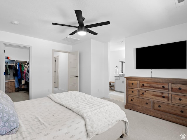 bedroom featuring light colored carpet, a walk in closet, visible vents, and a closet