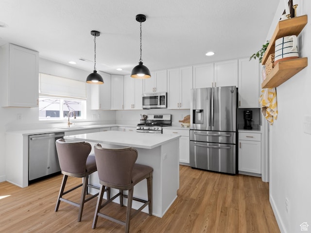 kitchen with a breakfast bar area, light countertops, white cabinets, a sink, and stainless steel appliances