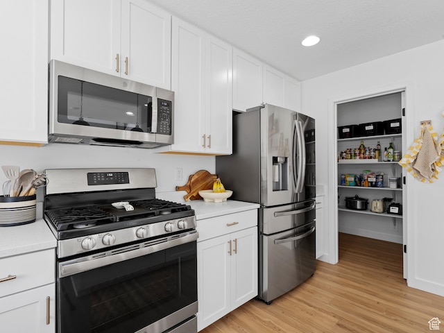 kitchen with light countertops, appliances with stainless steel finishes, light wood finished floors, and white cabinetry