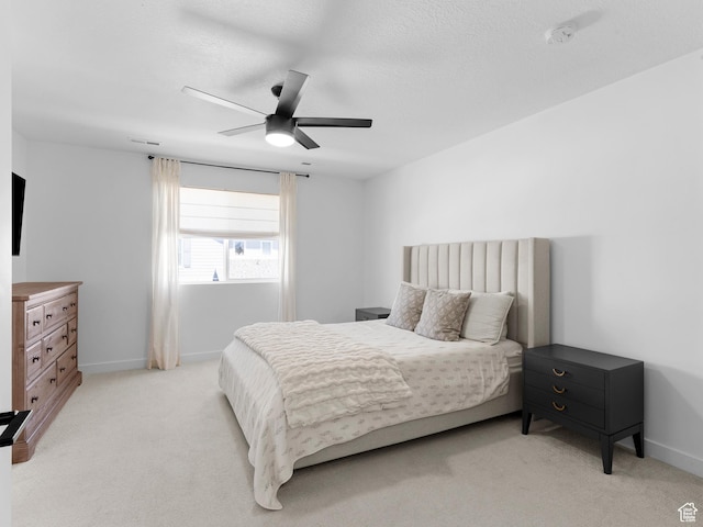bedroom featuring baseboards, light carpet, a ceiling fan, and visible vents
