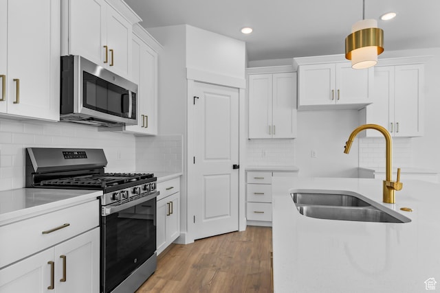 688 N 600 W Unit 104, Tremonton, UT 84337 - kitchen with appliances with stainless steel finishes, light countertops, white cabinets, decorative light fixtures, and wood finished floors