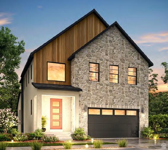contemporary home featuring an attached garage, driveway, and stone siding