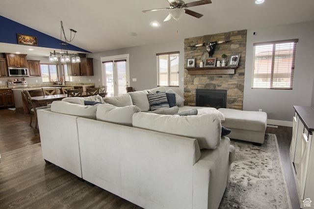 428 S Saddle Rd, Grantsville, UT 84029 - living area with lofted ceiling, a healthy amount of sunlight, a stone fireplace, dark wood-type flooring, and ceiling fan with notable chandelier
