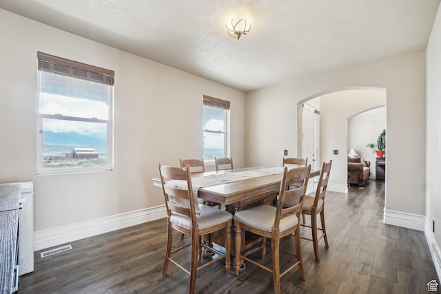 3214 W Ridgeline Rd, Stockton, UT 84071 - dining area featuring dark wood-style flooring, arched walkways, baseboards, and visible vents