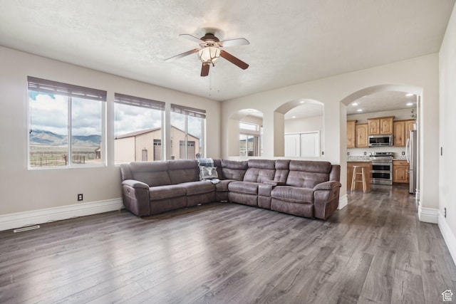 3214 W Ridgeline Rd, Stockton, UT 84071 - living area featuring arched walkways, ceiling fan, baseboards, and dark wood-style flooring