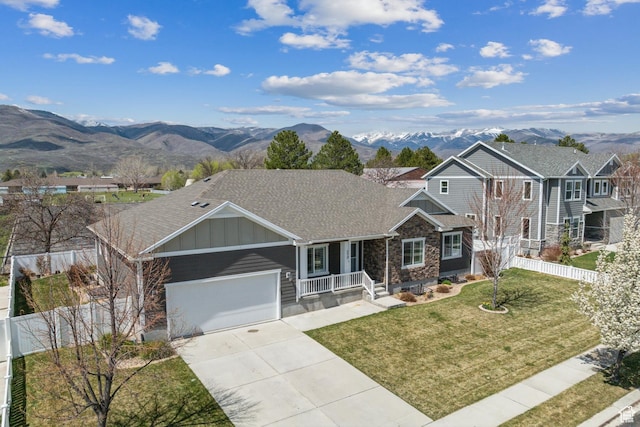 view of front of house with board and batten siding, a mountain view, a front yard, and concrete driveway