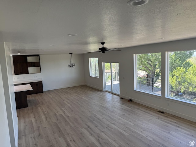 unfurnished living room with light wood-style floors, baseboards, ceiling fan, and visible vents
