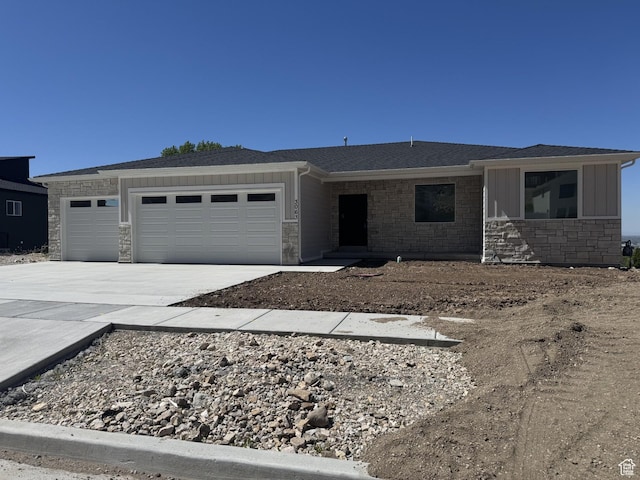 single story home with board and batten siding, roof with shingles, a garage, concrete driveway, and stone siding