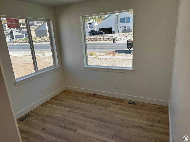 unfurnished dining area with baseboards, wood finished floors, and visible vents