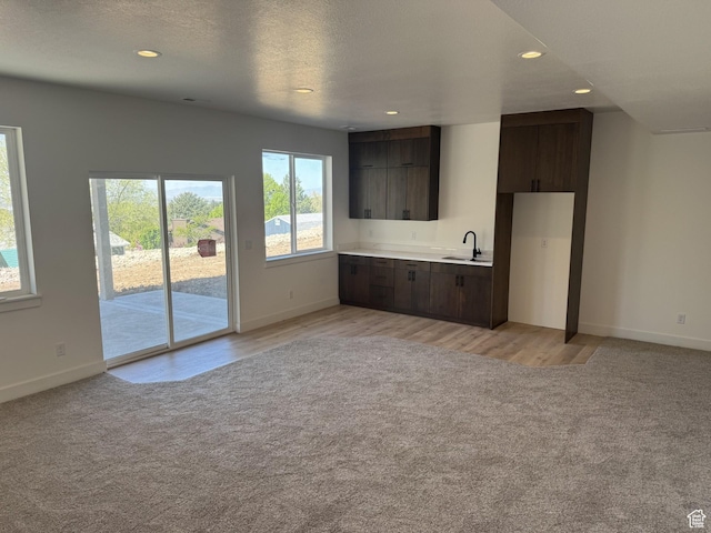 unfurnished living room with recessed lighting, a sink, and light carpet
