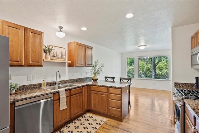 2948 W 150 N, Layton, UT 84041 - kitchen featuring stainless steel appliances, a sink, a peninsula, brown cabinetry, and a textured ceiling