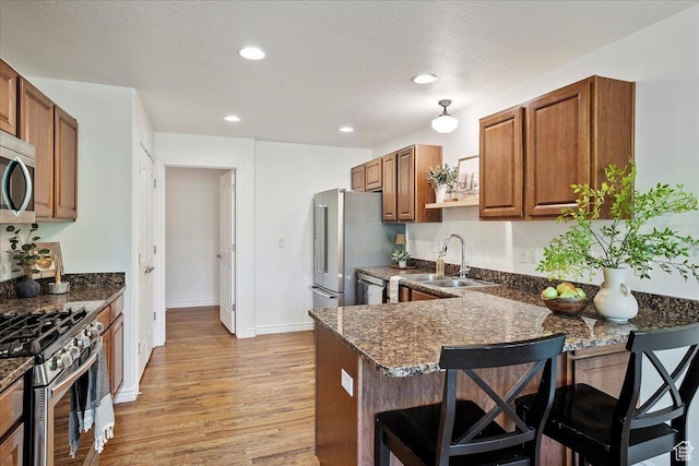 2948 W 150 N, Layton, UT 84041 - kitchen featuring appliances with stainless steel finishes, a sink, brown cabinetry, a breakfast bar area, and recessed lighting