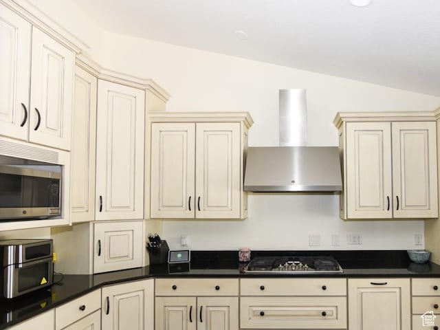 405 E Triple Crown Way E, Grantsville, UT 84029 - kitchen featuring wall chimney range hood, dark countertops, cream cabinets, and stainless steel appliances