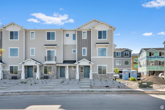 multi unit property featuring a residential view, central AC unit, and stone siding